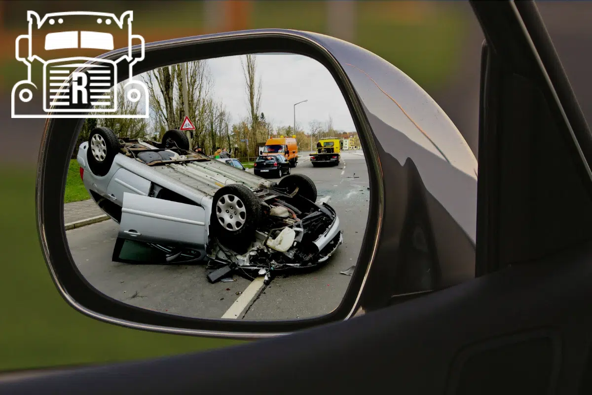 view from a side mirror showing a car that has rolled over